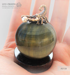 Bronze figure of scorpion on a Chrysoberyl sphere with sea pearl and Swarovski inserts on dolerite plate extra small  Бронзовый скорпион на сфере из кошачьего глаза с морской жемчужиной и вставками из Сваровски на пластине из долерита -малый