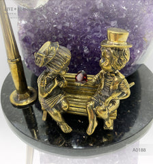 Bronze figures of cupid and sweethearts on a bench with a garnet heart on geodes amethyst agate background