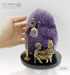 Bronze figures of cupid and sweethearts on a bench with a garnet heart on geodes amethyst agate background