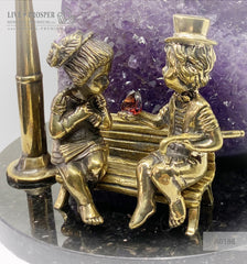 Bronze figures of cupid and sweethearts on a bench with a garnet heart on geodes amethyst agate background