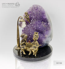 Bronze figures of cupid and sweethearts on a bench with a garnet heart on geodes amethyst agate background